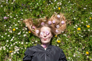 Girl lies in a flower meadow with daisies on her eyes and cherry blossoms in her hair Girl lies in a flower meadow with daisies on her eyes and cherry blossoms in her hair